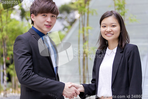 Image of Young Asian female and male business executive shaking hands