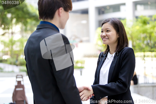 Image of Young Asian female and male business executive shaking hands