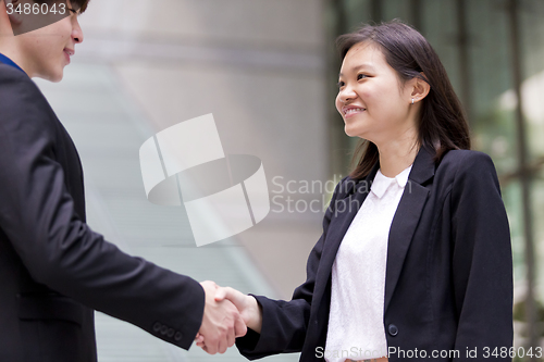 Image of Young Asian female and male business executive shaking hands