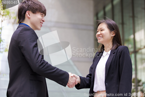 Image of Young Asian female and male business executive shaking hands