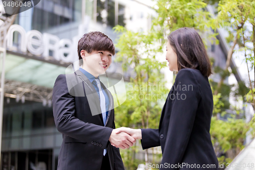 Image of Young Asian female and male business executive shaking hands