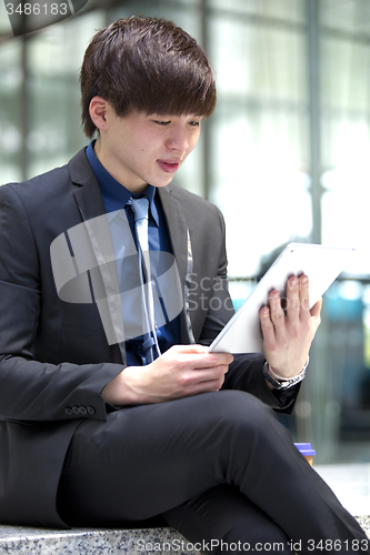 Image of Young Asian male business executive using table