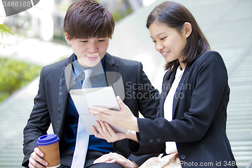 Image of Young Asian female and male business executive using table