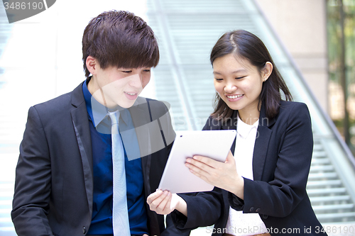 Image of Young Asian female and male business executive using table