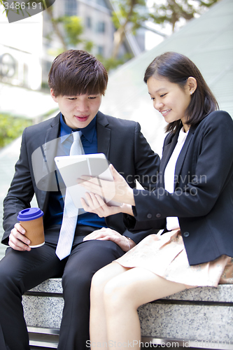 Image of Young Asian female and male business executive using table