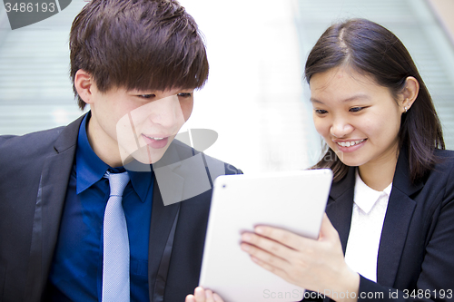 Image of Young Asian female and male business executive using table