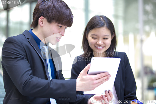 Image of Young Asian female and male business executive using table