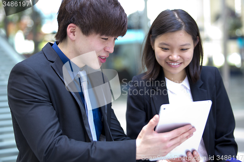 Image of Young Asian female and male business executive using tablet