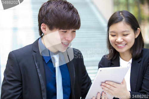 Image of Young Asian female and male business executive using tablet