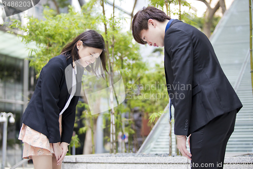 Image of Young Asian female and male business executive bowing to each other