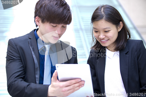 Image of Young Asian female and male business executive using tablet