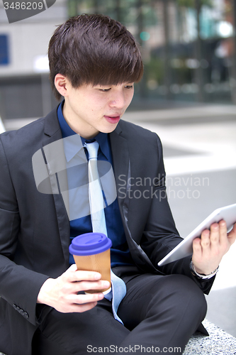 Image of Young Asian male business executive using tablet