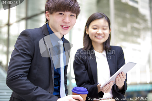 Image of Young Asian female and male business executive using tablet