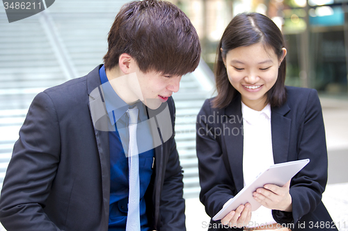 Image of Young Asian female and male business executive using tablet