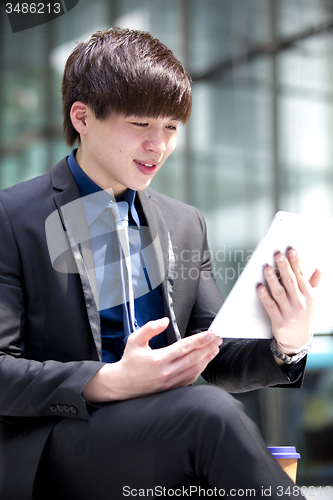 Image of Young Asian male business executive using tablet