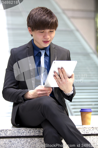Image of Young Asian male business executive using tablet