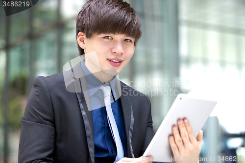 Image of Young Asian male business executive using tablet