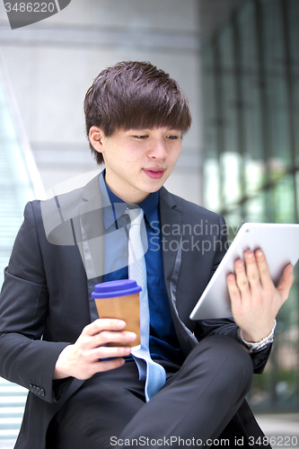 Image of Young Asian male business executive using tablet