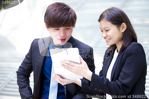 Image of Young Asian female and male business executive using tablet