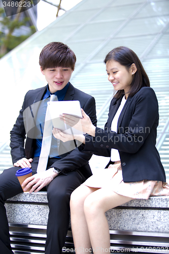 Image of Young Asian female and male business executive using tablet