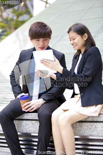 Image of Young Asian female and male business executive using tablet