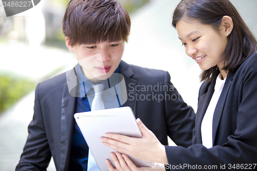 Image of Young Asian female and male business executive using tablet