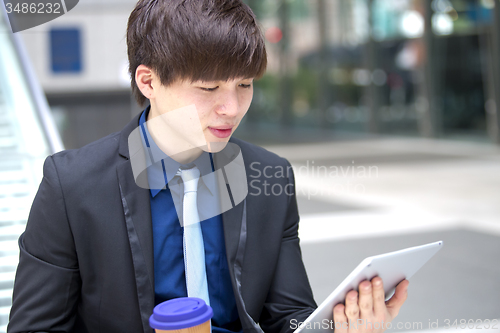 Image of Young Asian male business executive using tablet