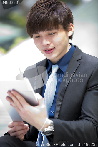 Image of Young Asian male business executive using tablet