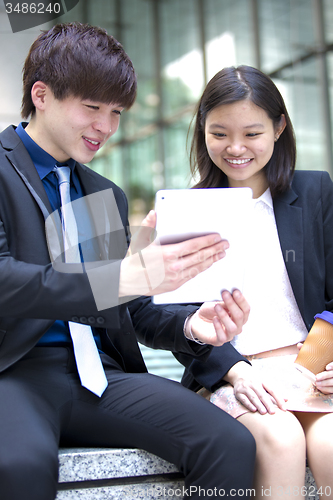 Image of Young Asian female and male business executive using tablet