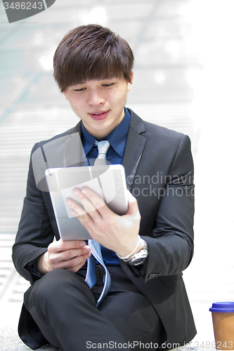 Image of Young Asian male business executive using tablet