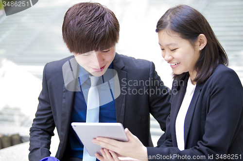 Image of Young Asian female and male business executive using tablet
