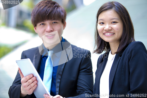 Image of Young Asian female and male business executive using tablet