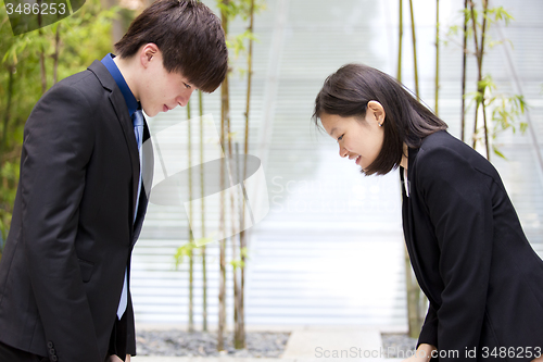 Image of Young Asian female and male business executive bowing to each other