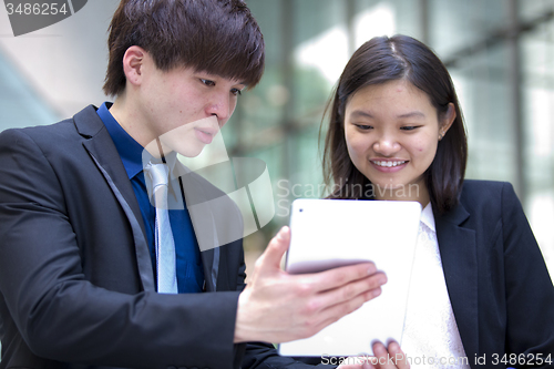 Image of Young Asian female and male business executive using tablet