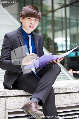 Image of Young Asian business executive in suit holding file