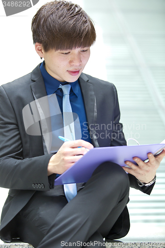 Image of Young Asian business executive in suit holding file