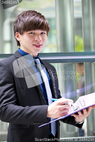 Image of Young Asian business executive in suit holding file