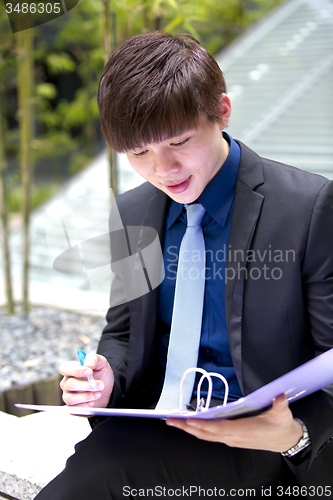 Image of Young Asian business executive in suit holding file