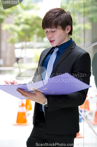 Image of Young Asian business executive in suit holding file