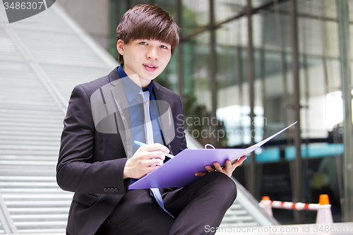 Image of Young Asian business executive in suit holding file