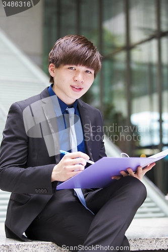 Image of Young Asian business executive in suit holding file