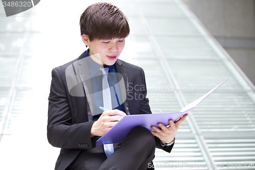 Image of Young Asian business executive in suit holding file