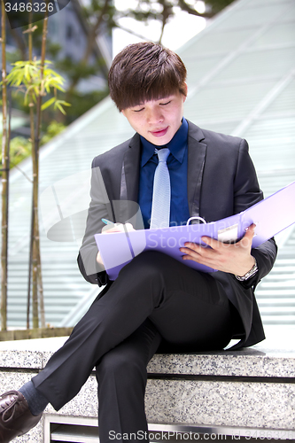 Image of Young Asian business executive in suit holding file