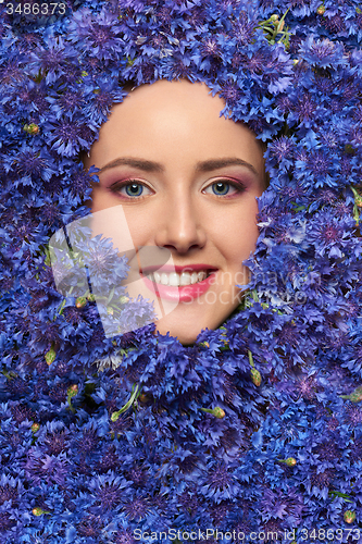 Image of Closeup  of woman face in cornflower flowers