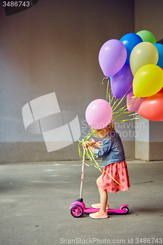 Image of happy little girl outdoors with balloons