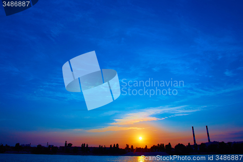 Image of factory in silhouette and sunrise sky