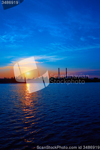 Image of factory in silhouette and sunrise sky