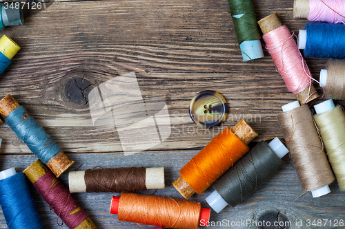 Image of one vintage button and coils of colored threads