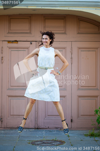 Image of Smiling beautiful middle-aged woman in the white dress flying