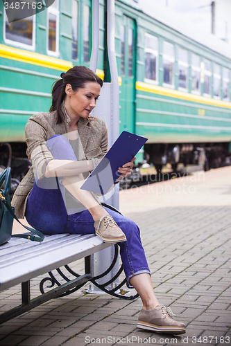 Image of beautiful woman traveler taking notes in a notebook